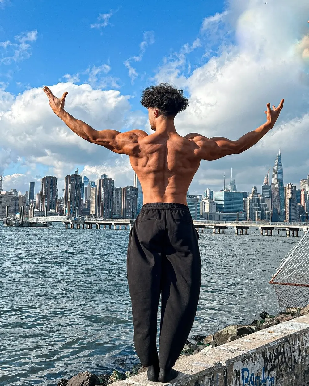 Rachid flexing his back in front of the New York skyline